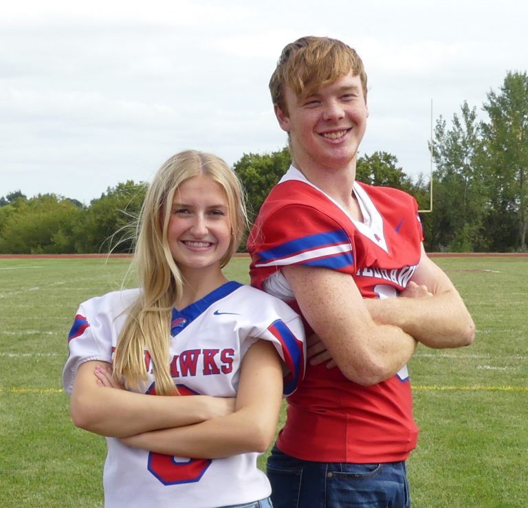 A thumbnail of a high school girl and boy in football jerseys standing side by side in a green football field during the day.