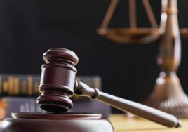 A photo of a wooden gavel in a courtroom setting.