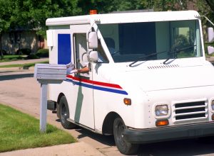 A postal truck used for delivering mail in a neighborhood on a sunny day.