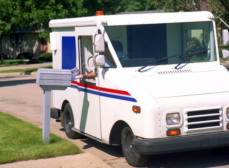 A postal truck used for delivering mail in a neighborhood on a sunny day.