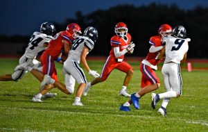 A group of football players in red try to outrun a group of football players in blue and white.