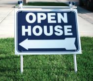 A blue and white sign on a green lawn with the words "Open House."
